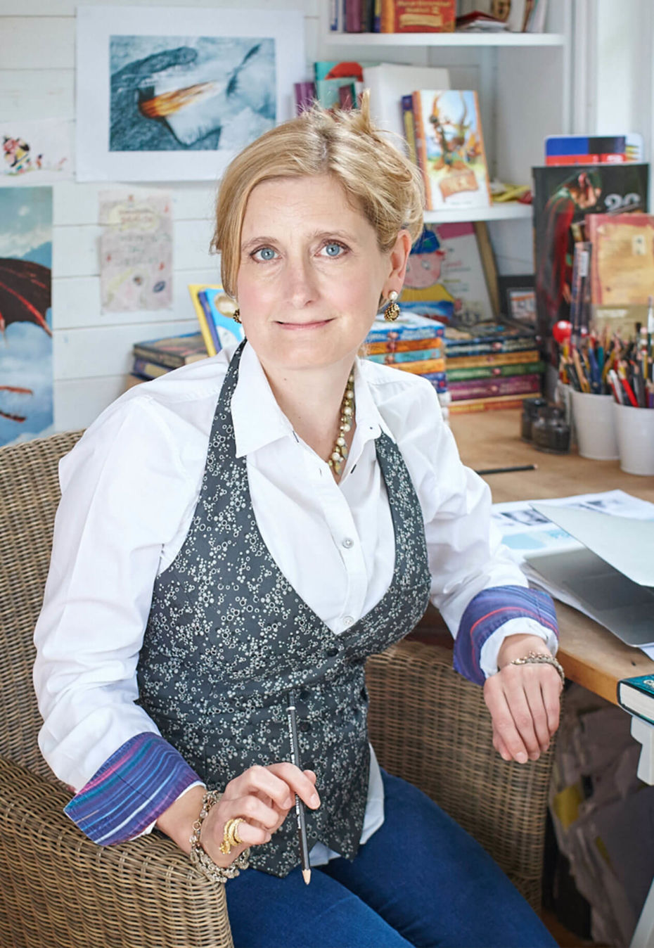 Portrait of Cressida Cowell sitting at her writing desk in her studio
