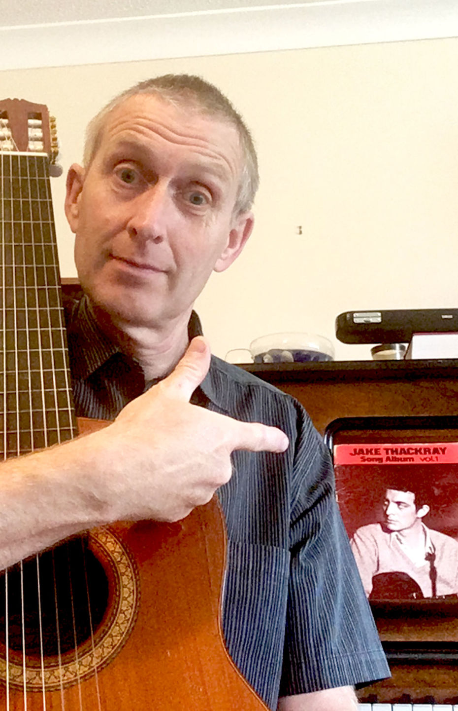 Portrait of Paul Thompson holding a guitar infant of a piano with a Jack Thackeray song sheet